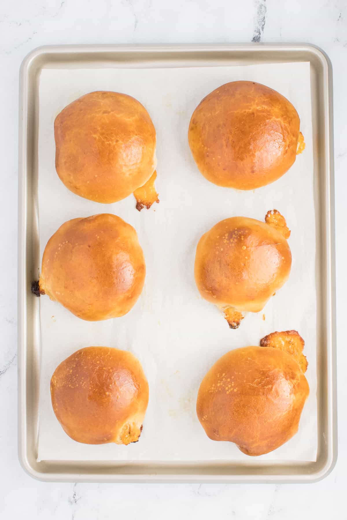 This image showcases baked runzas arranged on a baking pan. The runzas are cooked to a golden-brown perfection, displaying a delicious outer crust.