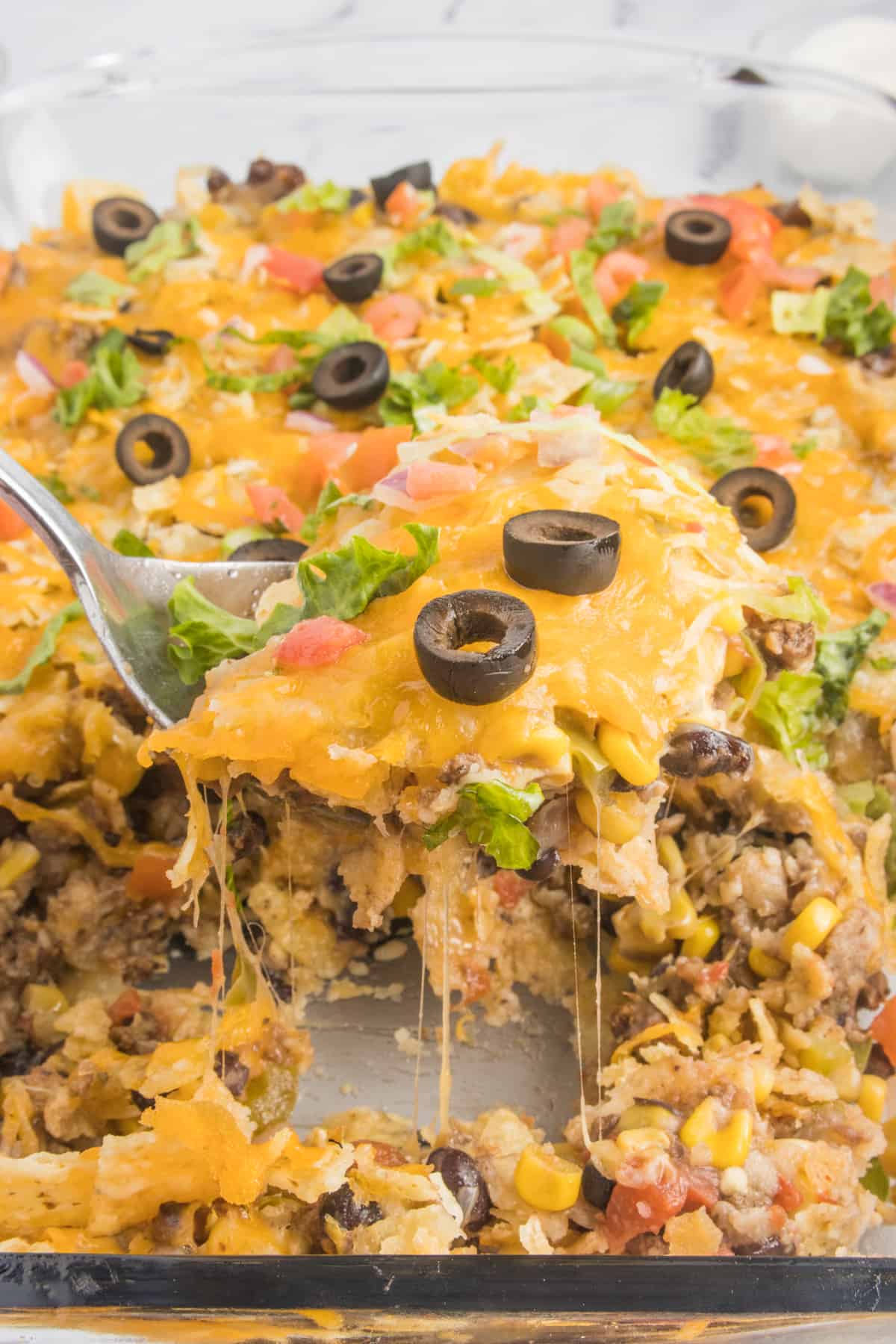 Close-up of a cheesy taco casserole on a spoon, with a tempting cheese pull.
