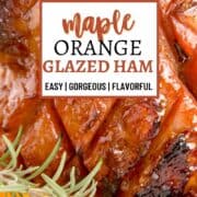 Glazed holiday ham garnished with fresh rosemary, cranberries and orange slices