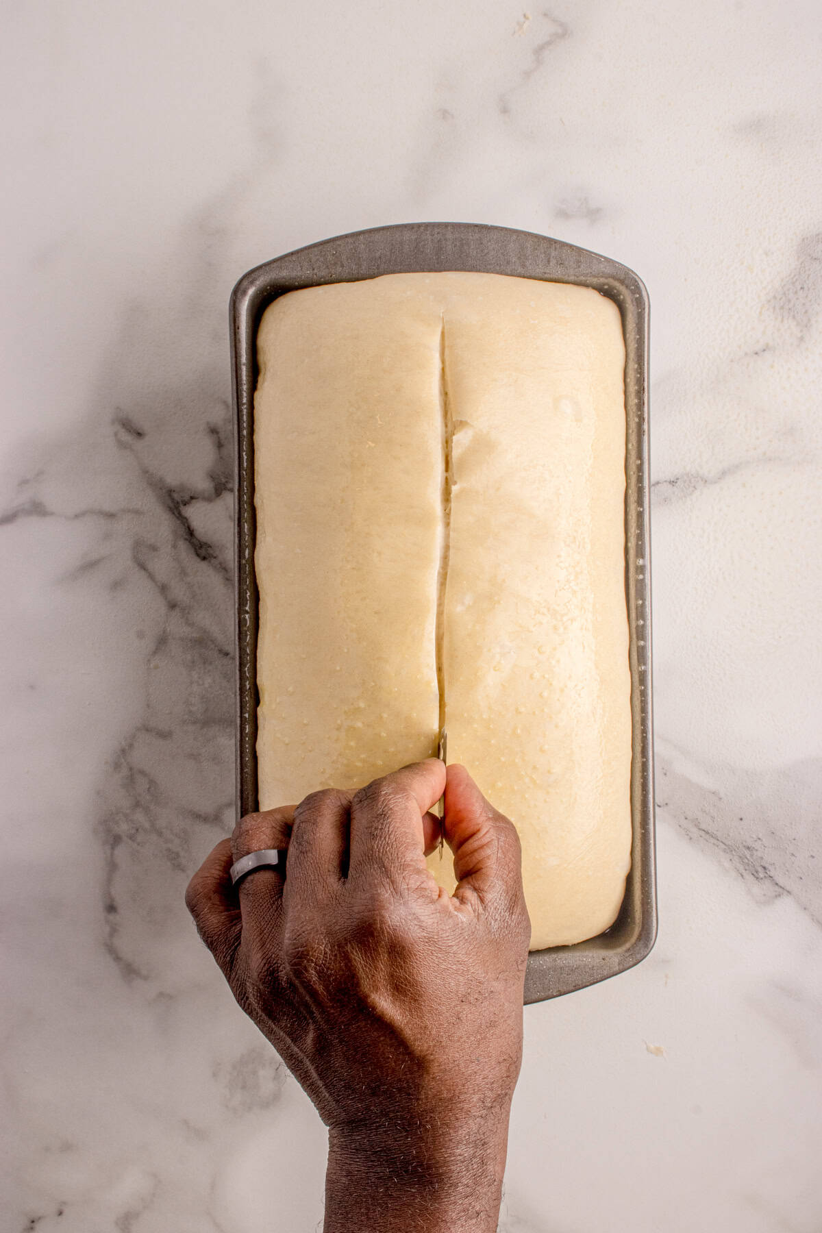 Hand scoring the loaf with a razor