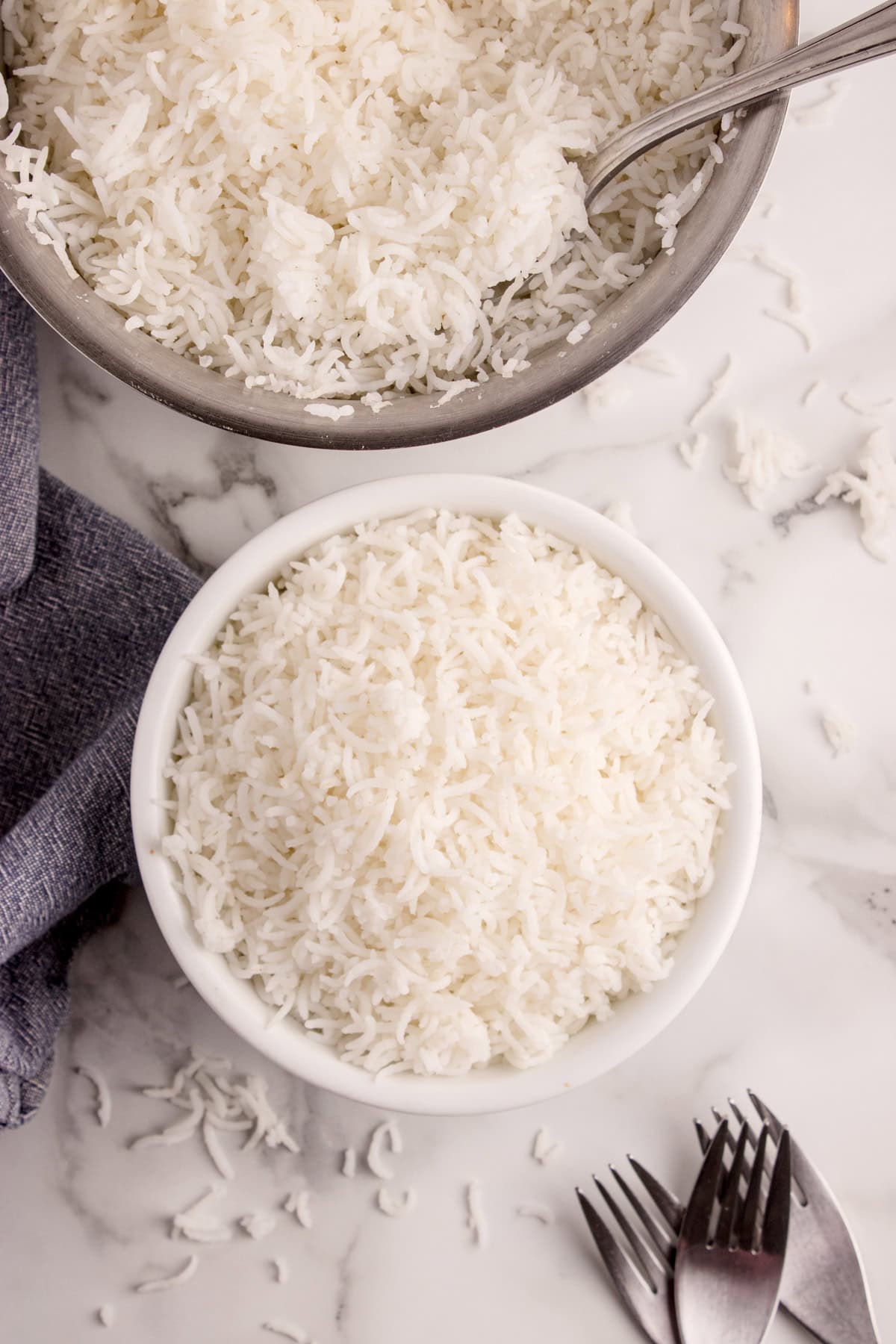 A bowl of rice and beside it is a saucepan that was used to cook the rice