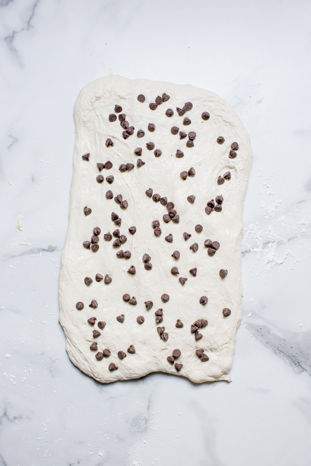 Flattened dough with chocolate chips on it.